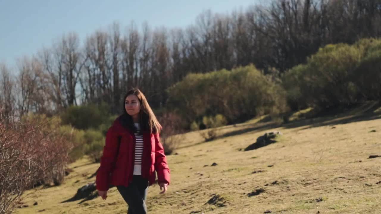 穿着红衣服的漂亮女人在大自然中徒步旅行。特写镜头。视频下载