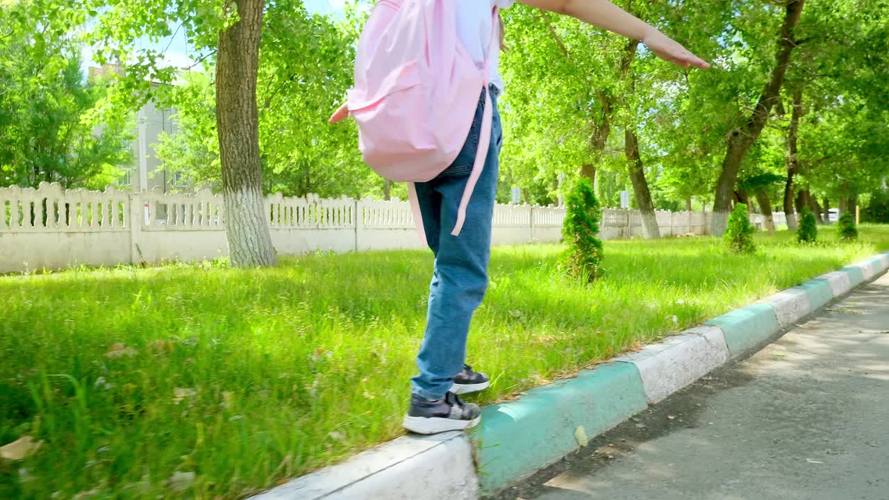 快乐的小女孩回到学校。孩子背着书包上学。背着背包的女孩走过校园。幸福家庭概念。回到学校。在学校操场上，一个女孩背着粉红色的背包去上学视频素材