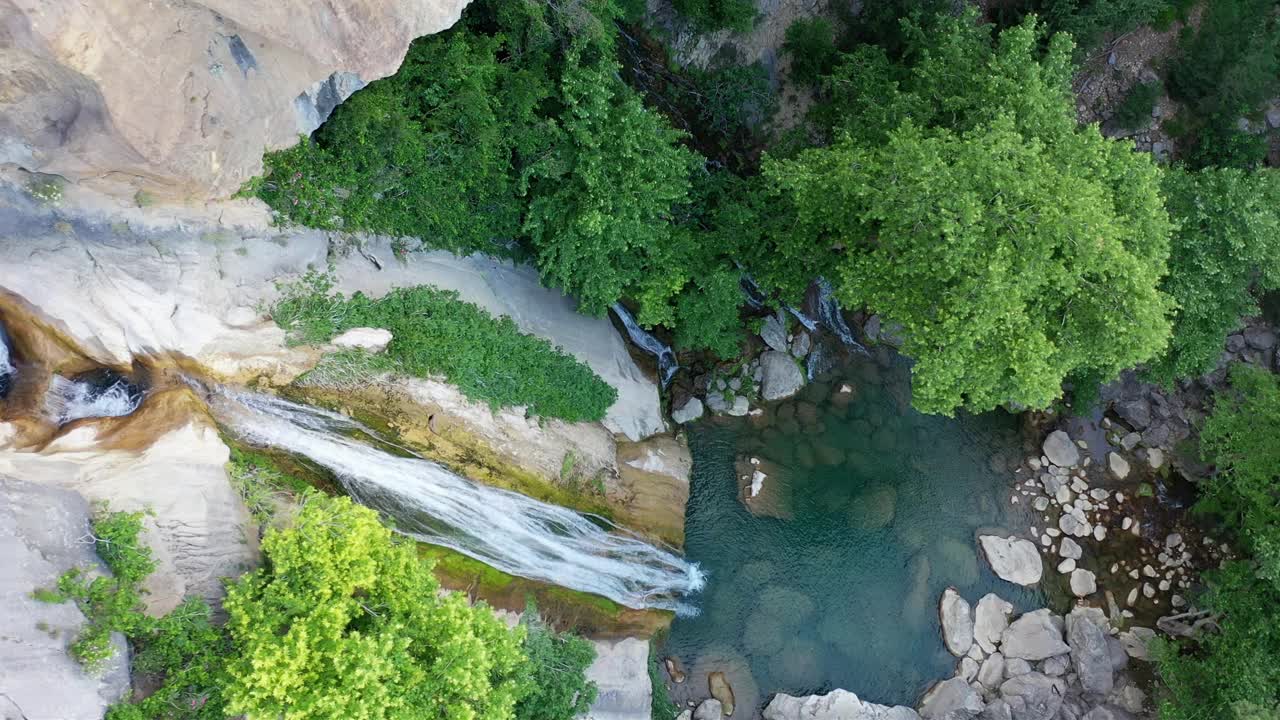 瀑布在绿树丛中高耸的山峰上壮丽的大自然中流淌，冰冷的水，从瀑布流下的水声宁静。周末度假的好去处。视频下载