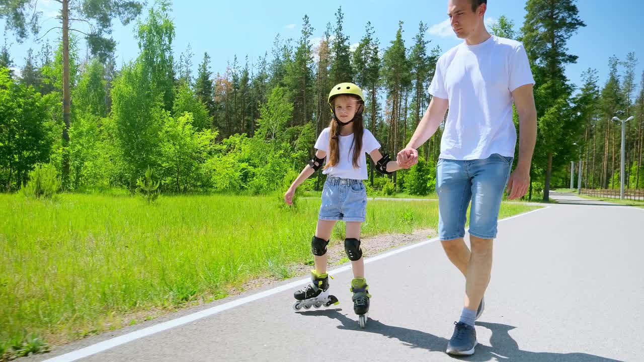 年轻的父亲走到镜头前，扶着正在学溜冰的女儿视频素材