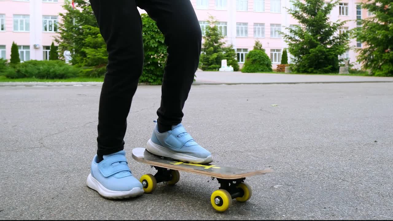 小女孩在柏油路上学习滑板。快乐的女孩在夏天骑滑冰在街上视频素材