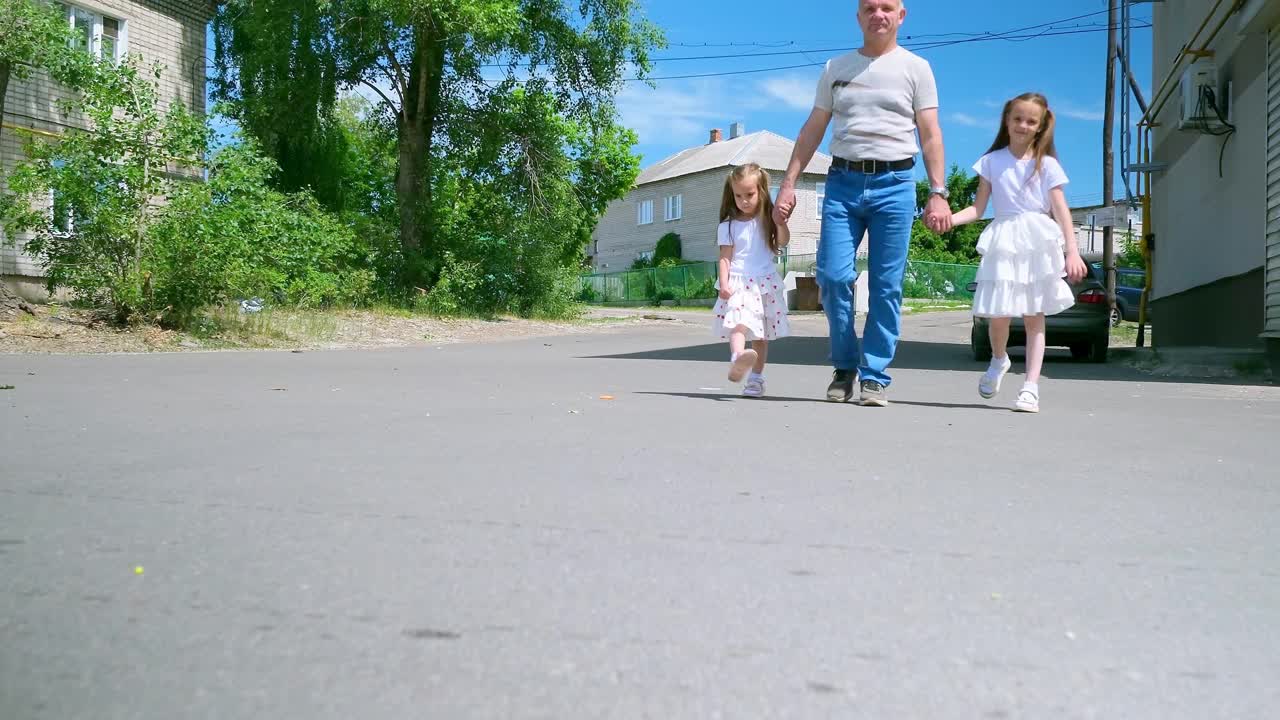 夏天，一位爷爷和他的小孙女们在操场上玩耍。视频素材