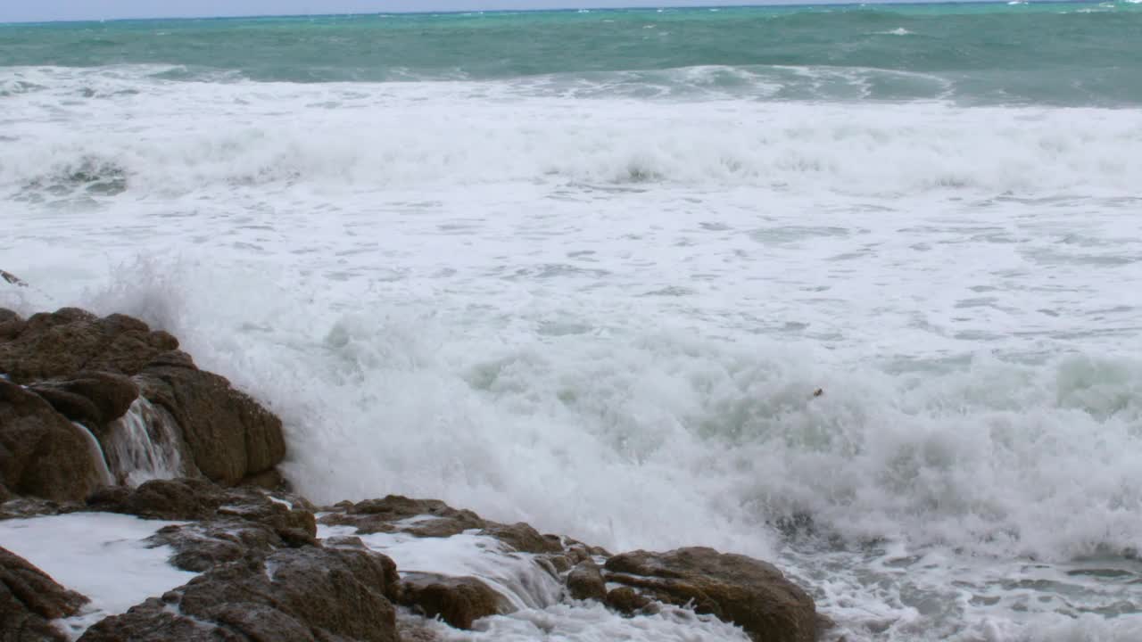 鸟瞰图在大海和岩石悬崖海滩，而绿松石海浪冲击悬崖岩石为夏季旅游假期的背景，从俯视图视频下载