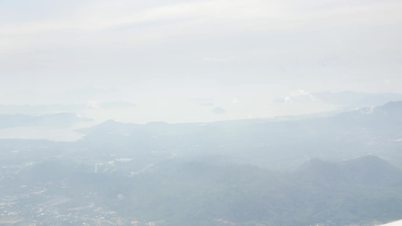 在阳光明媚的日子里，在海上、海岸、岛屿和海滩上空，飞机飞越云层时的鸟瞰图视频下载