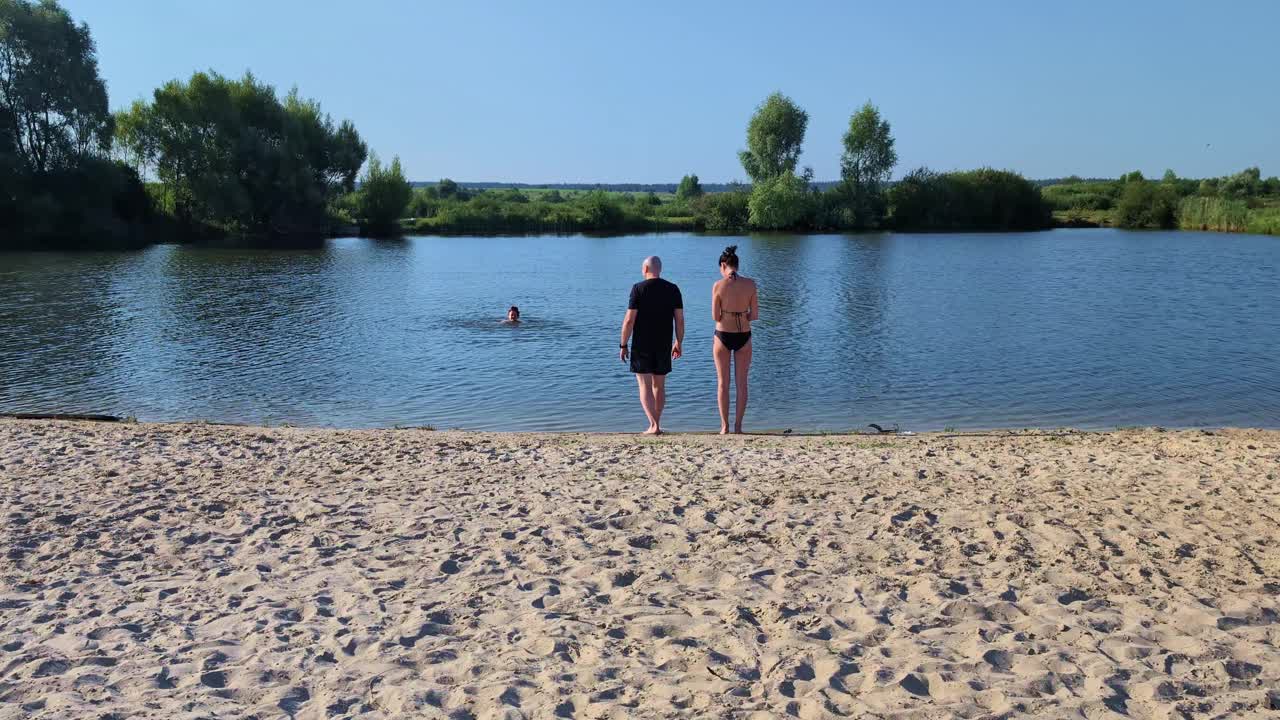 在一个炎热的夏日，一群人在一个风景优美的小湖中游泳，享受大自然的美丽和阳光的温暖视频下载