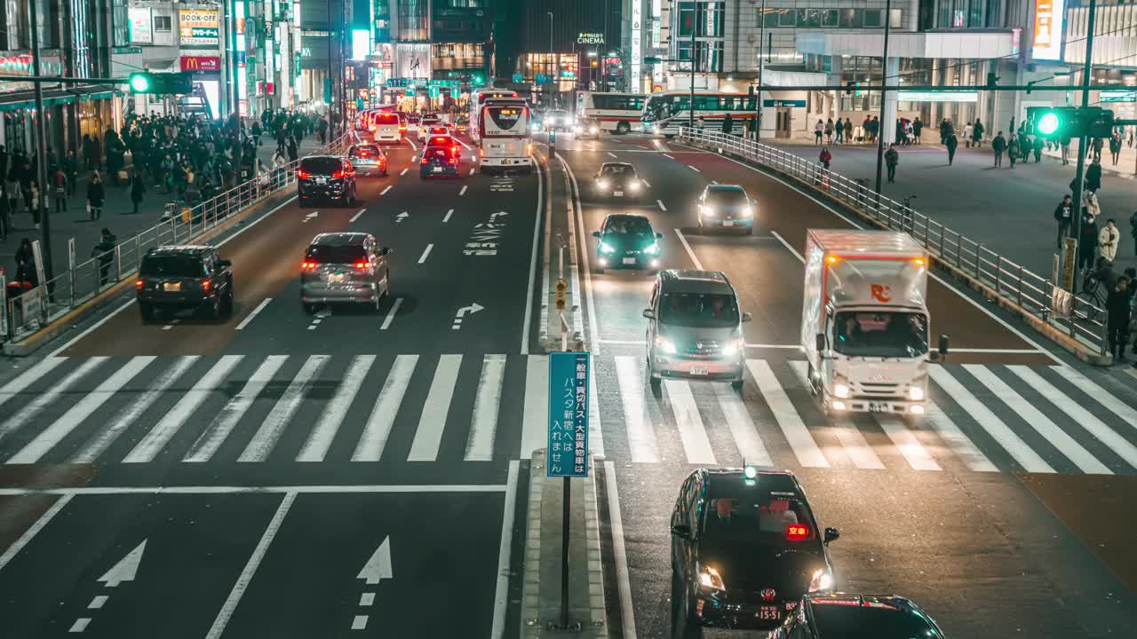 日本东京新宿地区火车站和高速公路公交车站附近，夜间人群在汽车行驶的街道上的时间流逝视频下载