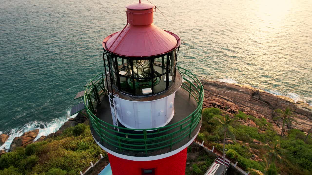 日落时海上海岸线上的灯塔，鸟瞰图。印度喀拉拉邦的Kovalam海滩和灯塔视频素材