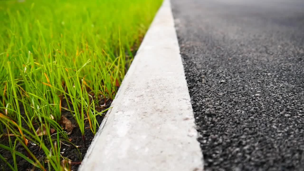 柏油路一侧的特写，后面的草坪被风吹动视频下载