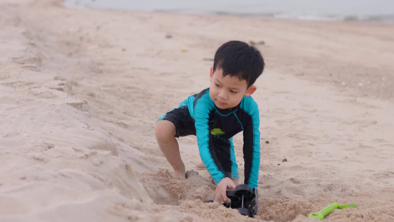 可爱的男孩在沙滩上玩沙和快乐视频下载