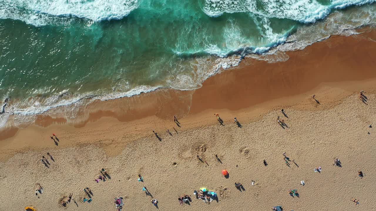 无人机拍摄的沙滩上的人们，海浪到达沙滩视频下载