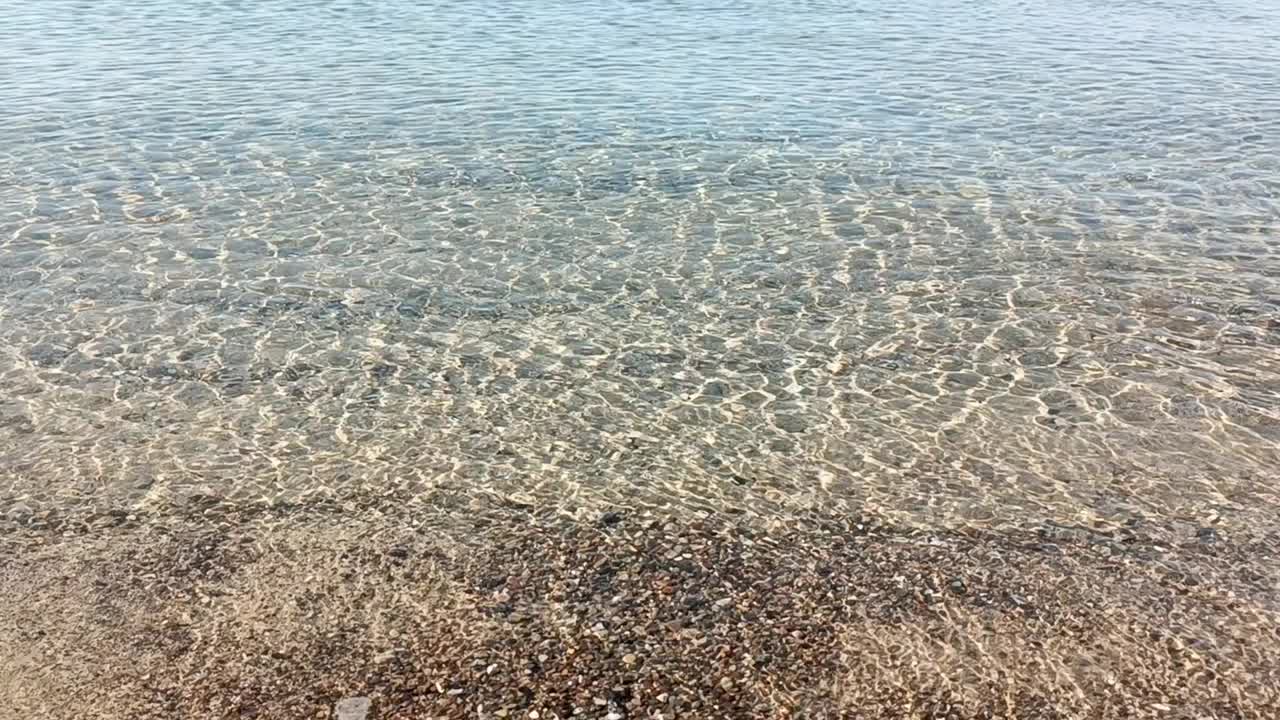 自然平静的大海背景。闪闪发光的海水和金色的沙子。夏日热带海滩上的海浪。阳光反射在水面上。浅浅的海水泛起涟漪。海床上的阳光。视频素材