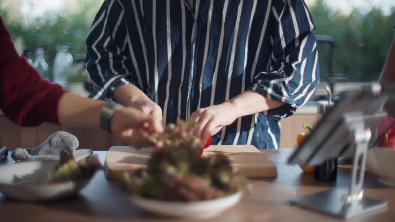 一个亚洲男人和朋友在家里的厨房里一起准备食物和沙拉。视频下载