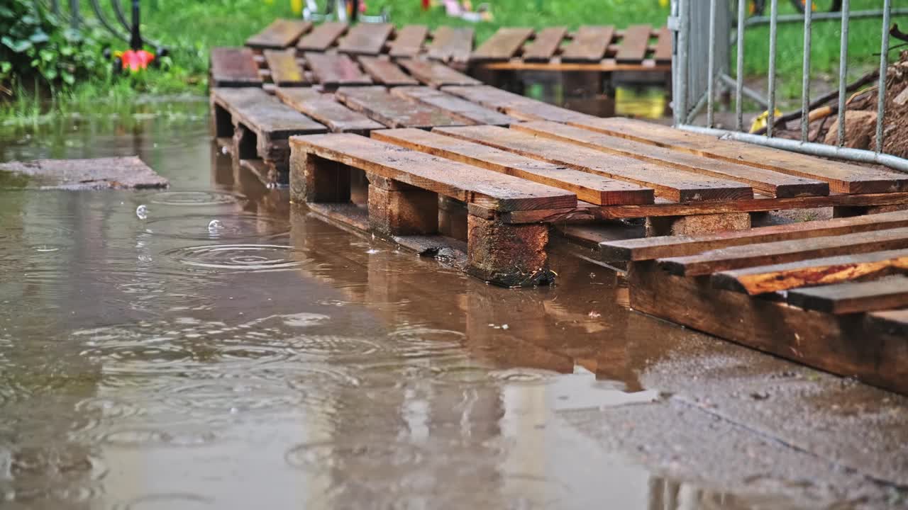 大雨后被水淹没的人行道上用木质运输货盘作临时行人通道视频下载