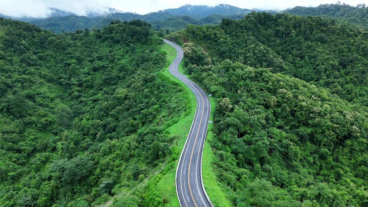 无人机在阳光下盘旋在蜿蜒的道路上，蜿蜒的柏油路穿过热带雨林。乡村景观。泰国南省的标志性旅游景点。视频素材