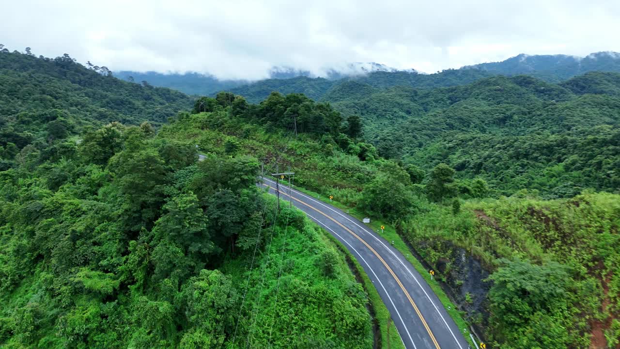 无人机在阳光下盘旋在蜿蜒的道路上，蜿蜒的柏油路穿过热带雨林。乡村景观。泰国南省的标志性旅游景点。视频素材