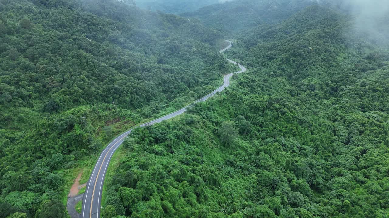 无人机在阳光下盘旋在蜿蜒的道路上，蜿蜒的柏油路穿过热带雨林。乡村景观。泰国南省的标志性旅游景点。视频素材