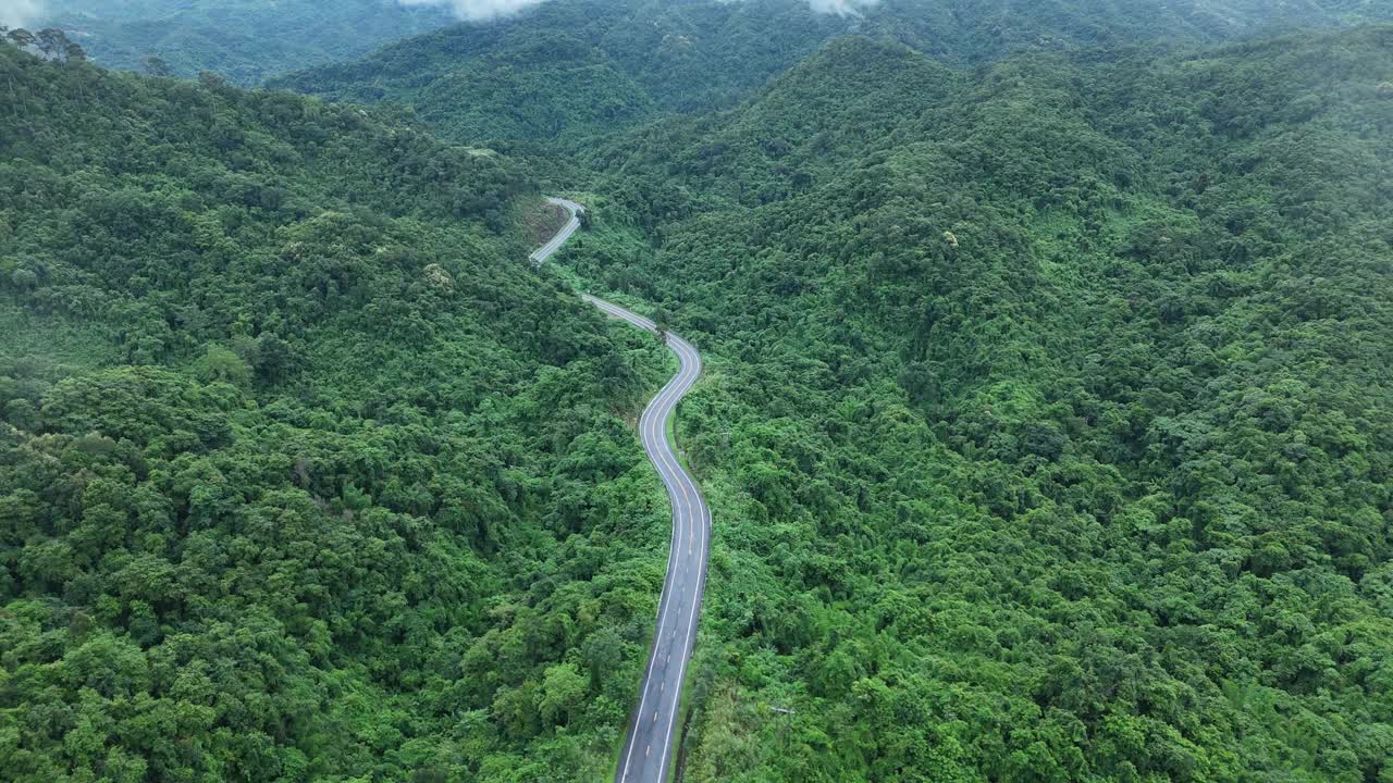 无人机在阳光下盘旋在蜿蜒的道路上，蜿蜒的柏油路穿过热带雨林。乡村景观。泰国南省的标志性旅游景点。视频下载