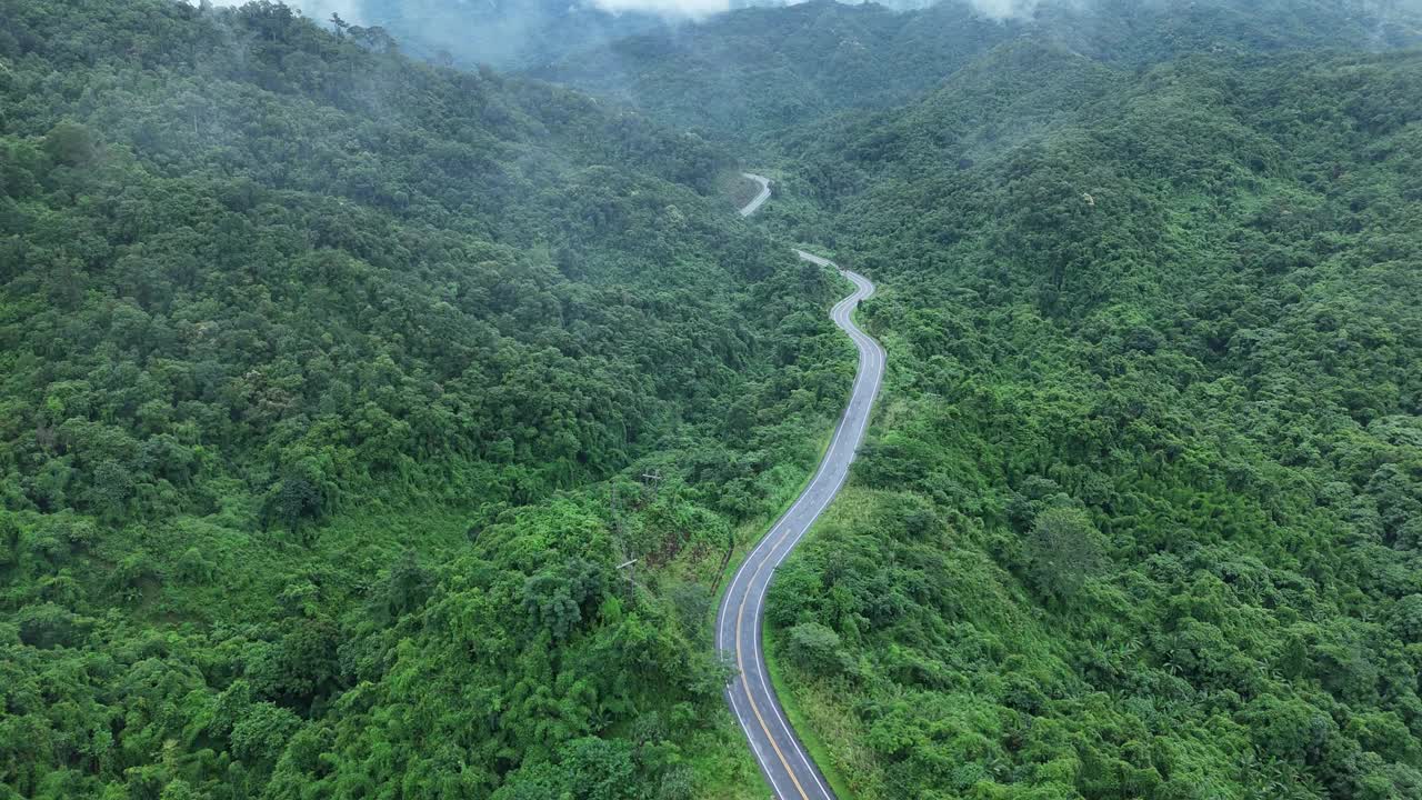 无人机在阳光下盘旋在蜿蜒的道路上，蜿蜒的柏油路穿过热带雨林。乡村景观。泰国南省的标志性旅游景点。视频素材