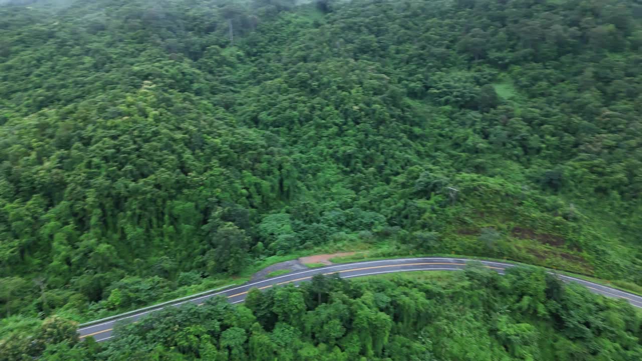 无人机在阳光下盘旋在蜿蜒的道路上，蜿蜒的柏油路穿过热带雨林。乡村景观。泰国南省的标志性旅游景点。视频下载