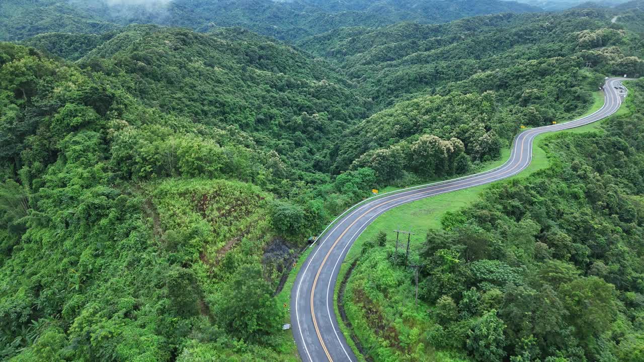 无人机在阳光下盘旋在蜿蜒的道路上，蜿蜒的柏油路穿过热带雨林。乡村景观。泰国南省的标志性旅游景点。视频下载