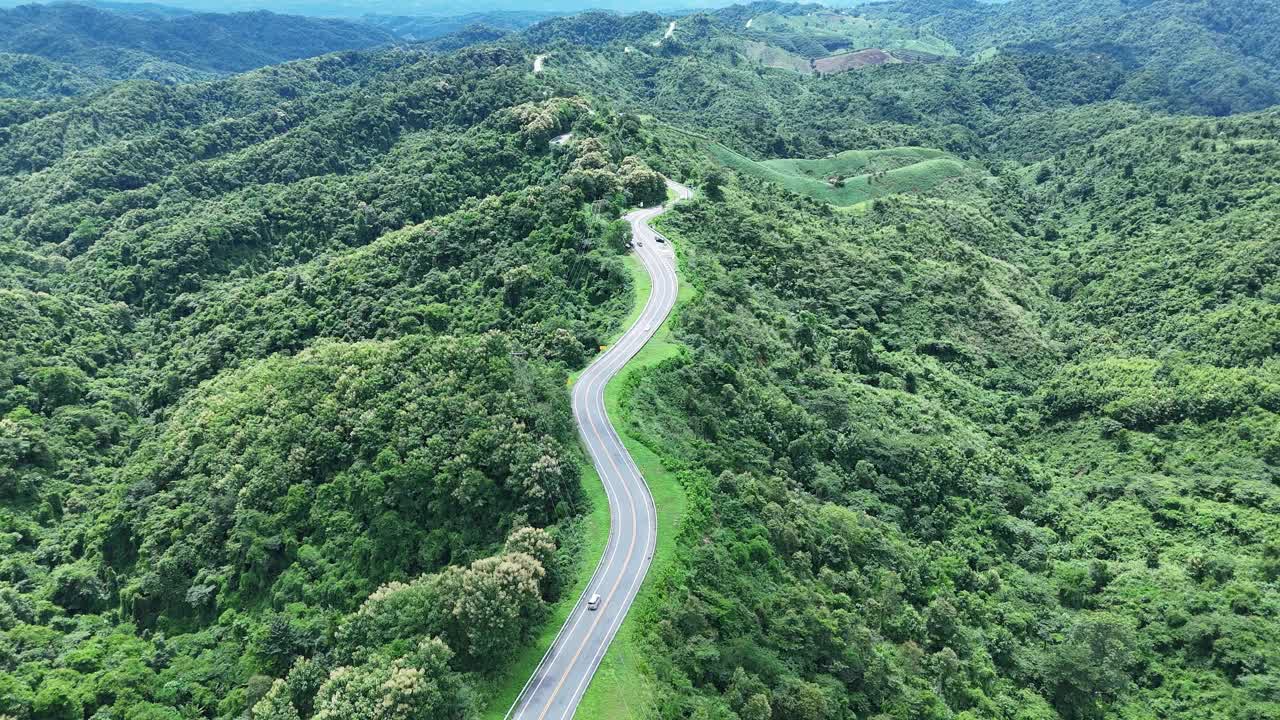 无人机在阳光下盘旋在蜿蜒的道路上，蜿蜒的柏油路穿过热带雨林。乡村景观。泰国南省的标志性旅游景点。视频下载