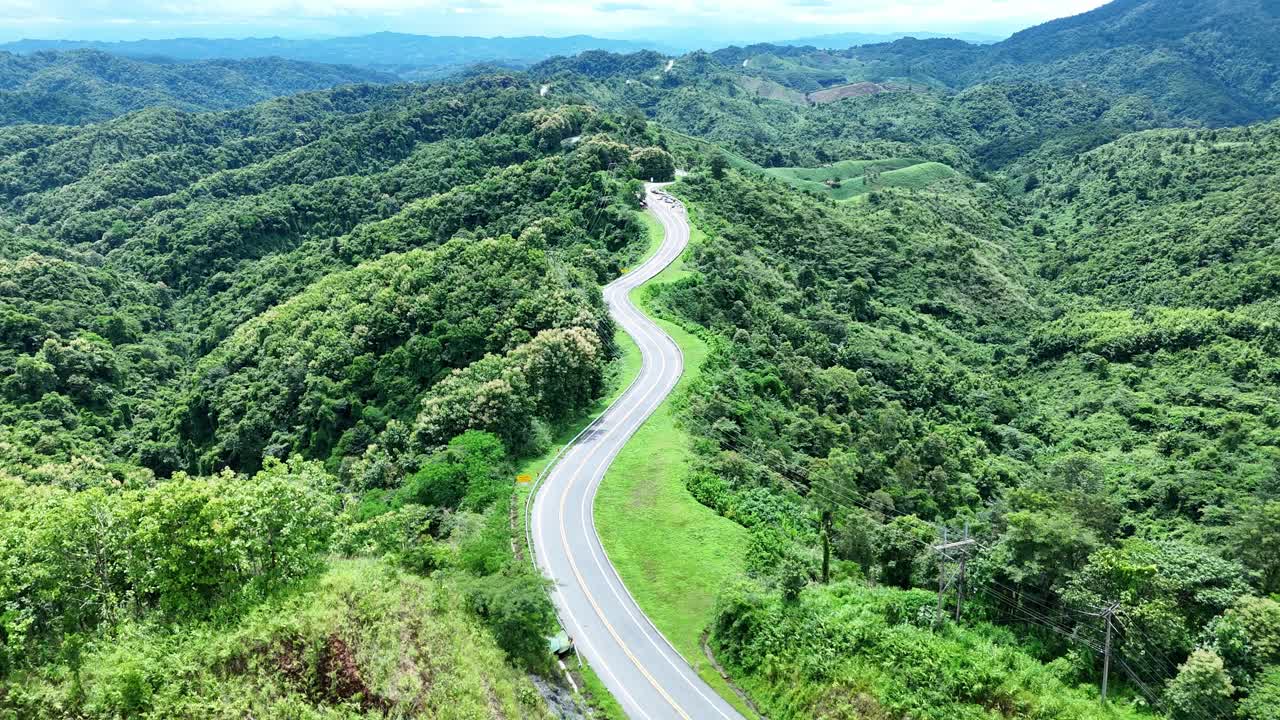 无人机在阳光下盘旋在蜿蜒的道路上，蜿蜒的柏油路穿过热带雨林。乡村景观。泰国南省的标志性旅游景点。视频下载