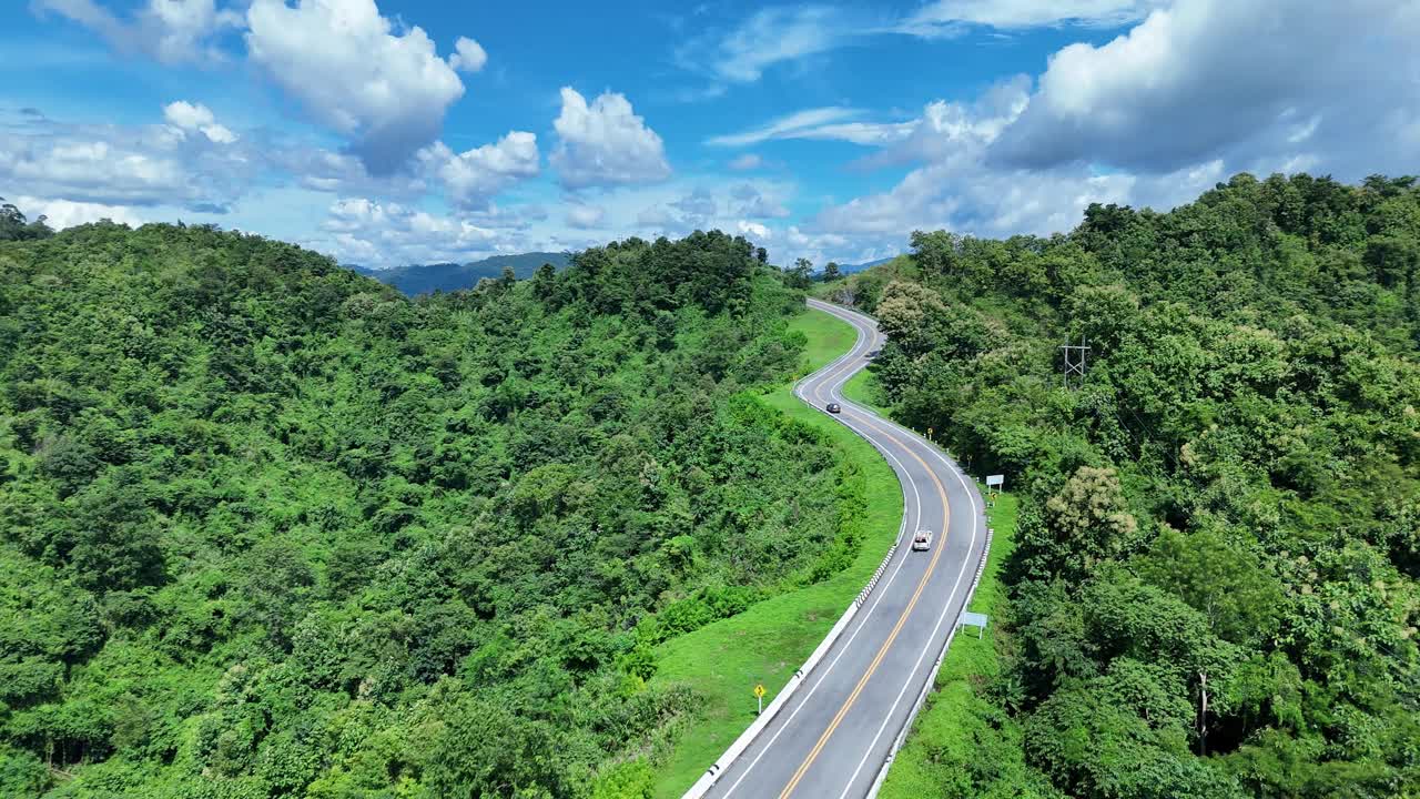 无人机在阳光下盘旋在蜿蜒的道路上，蜿蜒的柏油路穿过热带雨林。乡村景观。泰国南省的标志性旅游景点。视频下载