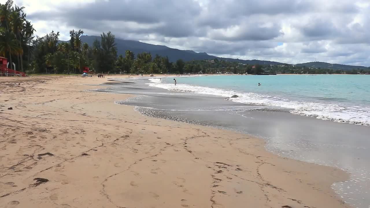 水冲在岸边美丽的海滩在波多黎各卢基洛(加勒比海岛屿旅游度假度假)田园诗般的空受欢迎的酒店旅游el yunque海浪冲浪沙滩云棕榈树视频下载