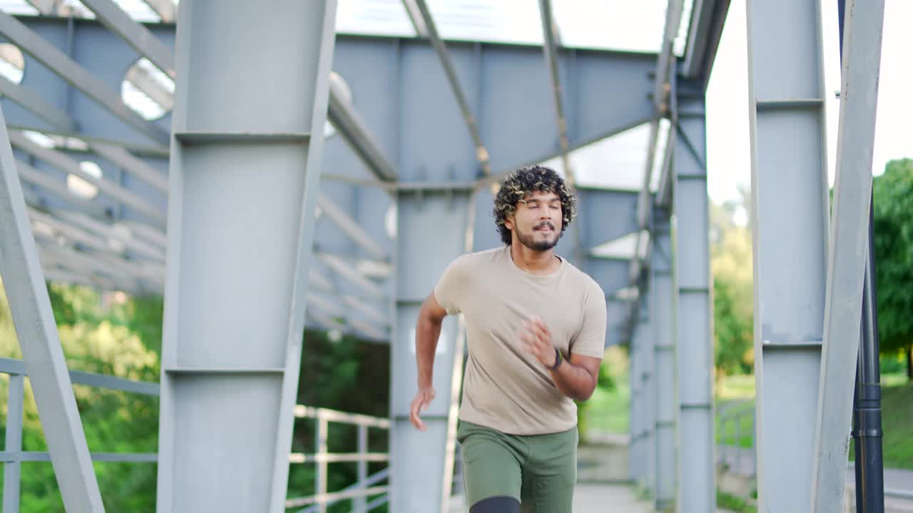 精力充沛的男性在城市体育场的桥下慢跑，拥抱健身和健康。视频素材