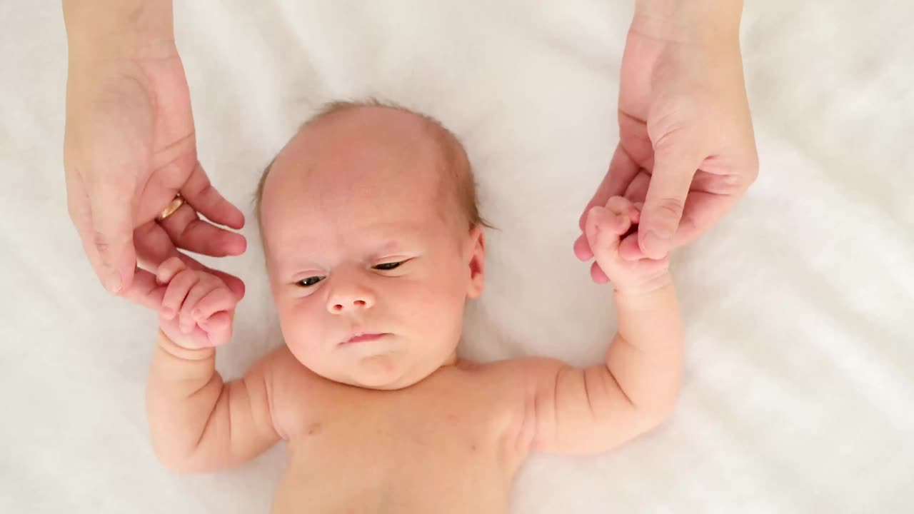 一个新生婴儿的特写肖像，躺在家里的一张白色床上，一个文字的地方。床上有个穿着尿布的小婴儿，俯视图视频下载