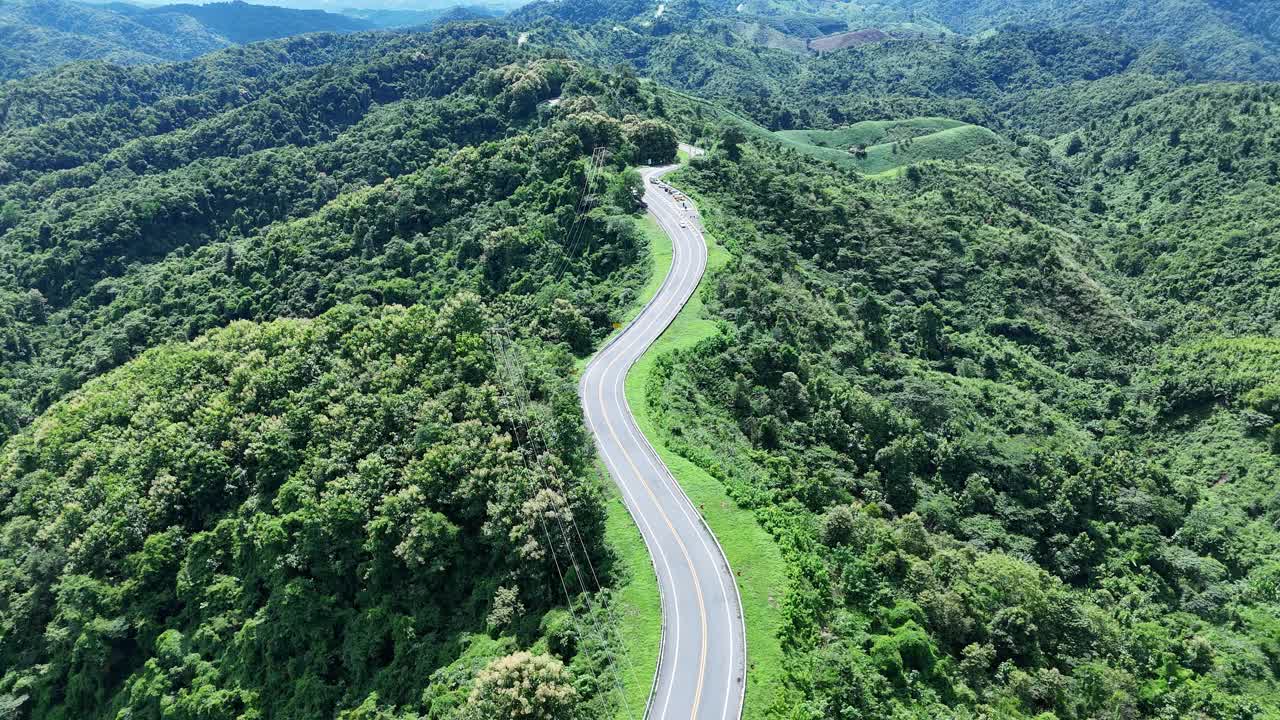 无人机在阳光下盘旋在蜿蜒的道路上，蜿蜒的柏油路穿过热带雨林。乡村景观。泰国南省的标志性旅游景点。视频素材