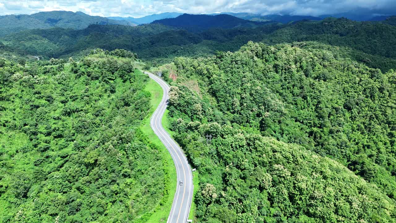 无人机在阳光下盘旋在蜿蜒的道路上，蜿蜒的柏油路穿过热带雨林。乡村景观。泰国南省的标志性旅游景点。视频素材