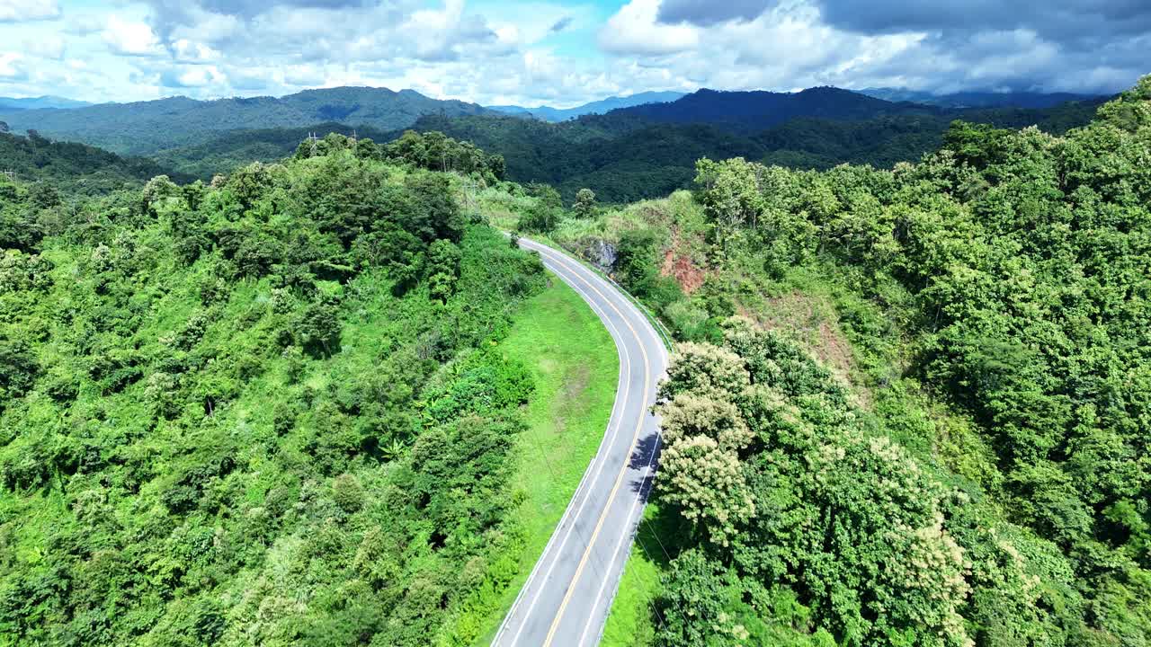 无人机在阳光下盘旋在蜿蜒的道路上，蜿蜒的柏油路穿过热带雨林。乡村景观。泰国南省的标志性旅游景点。视频素材