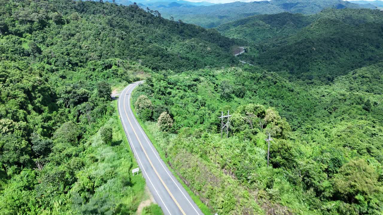 无人机在阳光下盘旋在蜿蜒的道路上，蜿蜒的柏油路穿过热带雨林。乡村景观。泰国南省的标志性旅游景点。视频下载