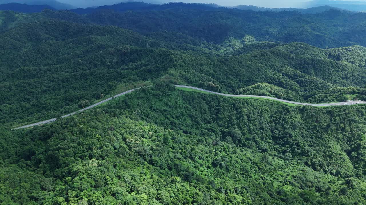 无人机在阳光下盘旋在蜿蜒的道路上，蜿蜒的柏油路穿过热带雨林。乡村景观。泰国南省的标志性旅游景点。视频下载