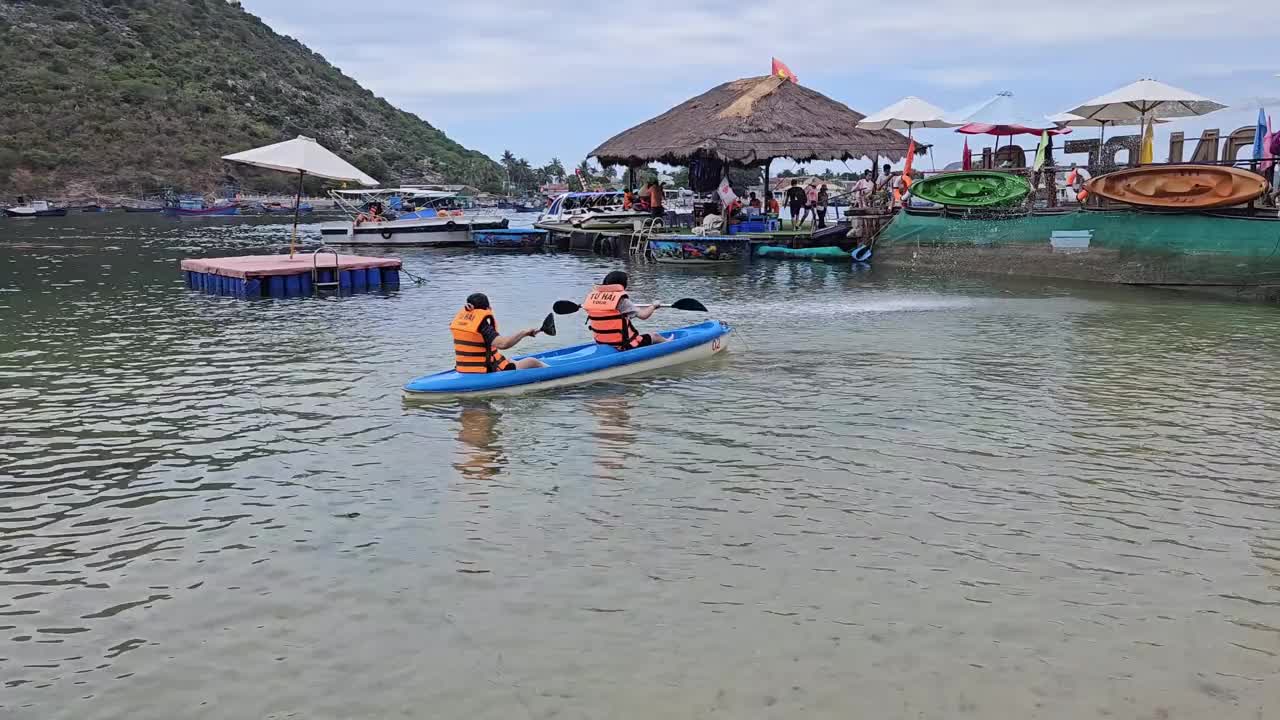 一群游客在芽庄市的海滩上乘坐双人皮艇。人们放松心情，享受海上航行。视频下载