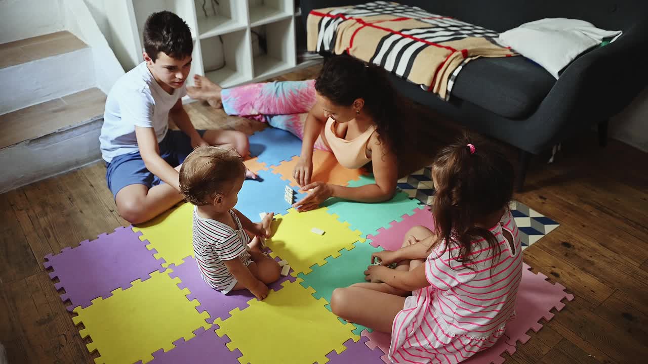 一家人在舒适的家庭环境中与年幼的孩子一起享受彩色游戏垫的美好时光视频素材