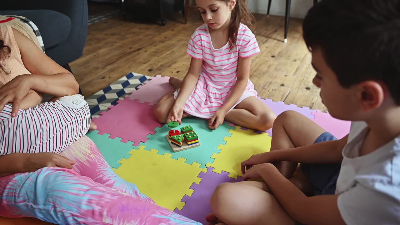 孩子们在家中与家人一起玩彩色的游戏垫，在舒适的客厅环境中享受美好的时光，营造出温暖而有趣的氛围。视频素材