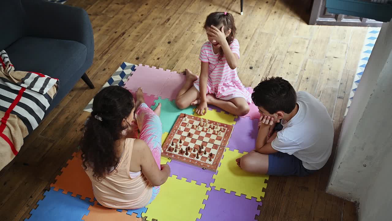 家庭纽带通过一个有趣的棋盘游戏，孩子和成人享受一个竞争游戏的国际象棋在一个五颜六色的游戏垫在家里视频素材