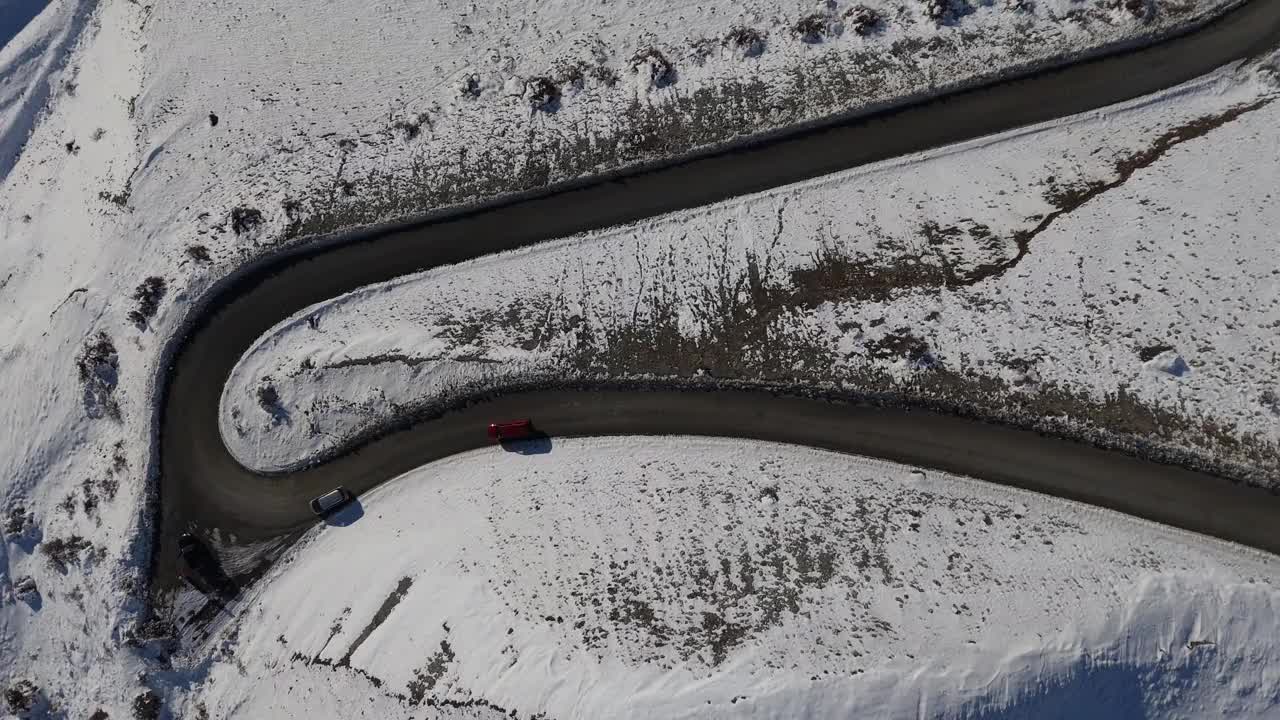 汽车小心翼翼地行驶在被雪包围的蜿蜒道路上视频下载