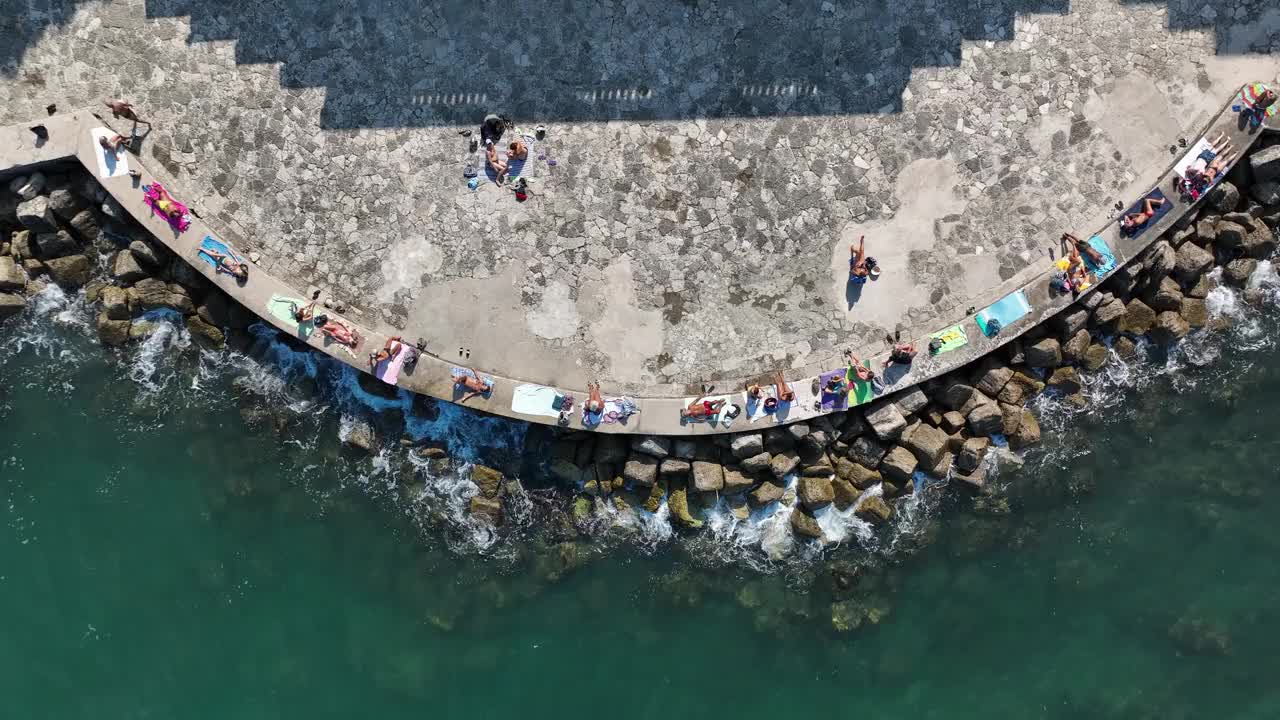 放松的海滩游客沿着岩石海岸线在沿海地区晒日光浴视频素材