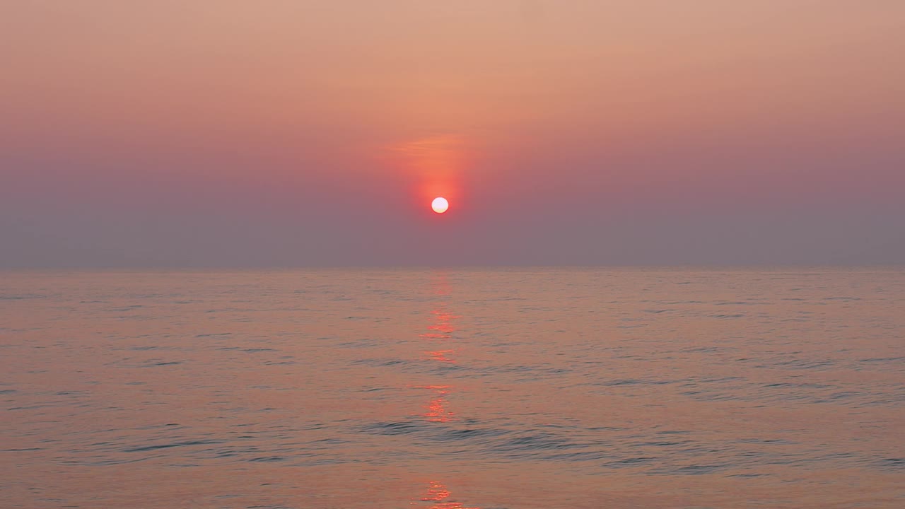 宁静的日落在平静的海水上，展示了充满活力的橙色和粉红色的天空，完美的宁静自然和美丽的主题。视频下载