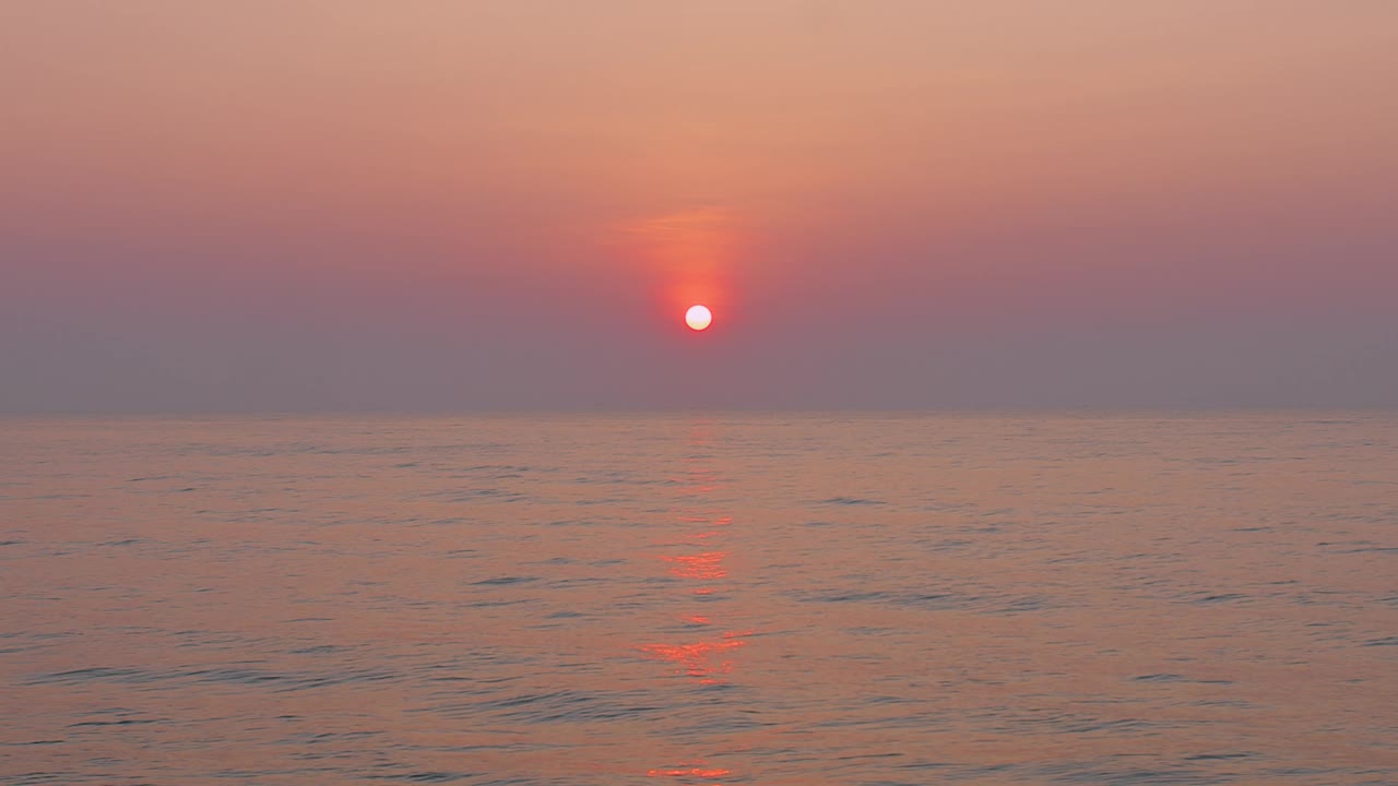 宁静的日落在平静的海水上，展示了充满活力的橙色和粉红色的天空，完美的宁静自然和美丽的主题。视频素材