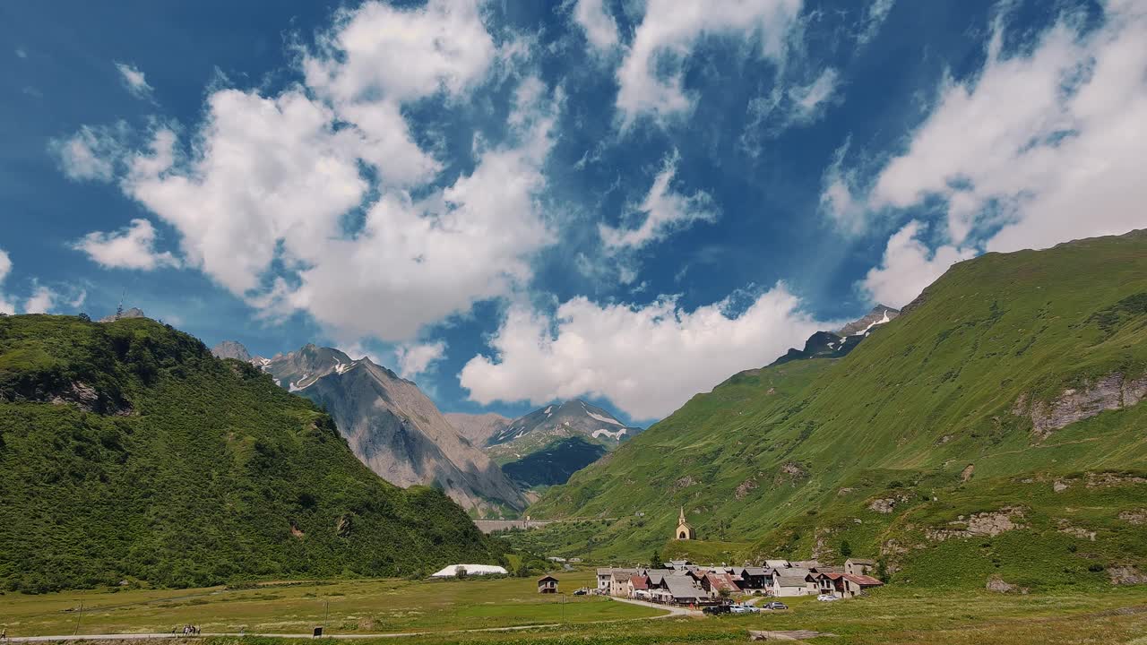 夏季高山村庄与郁郁葱葱的绿色草地和雄伟的山的背景视频素材