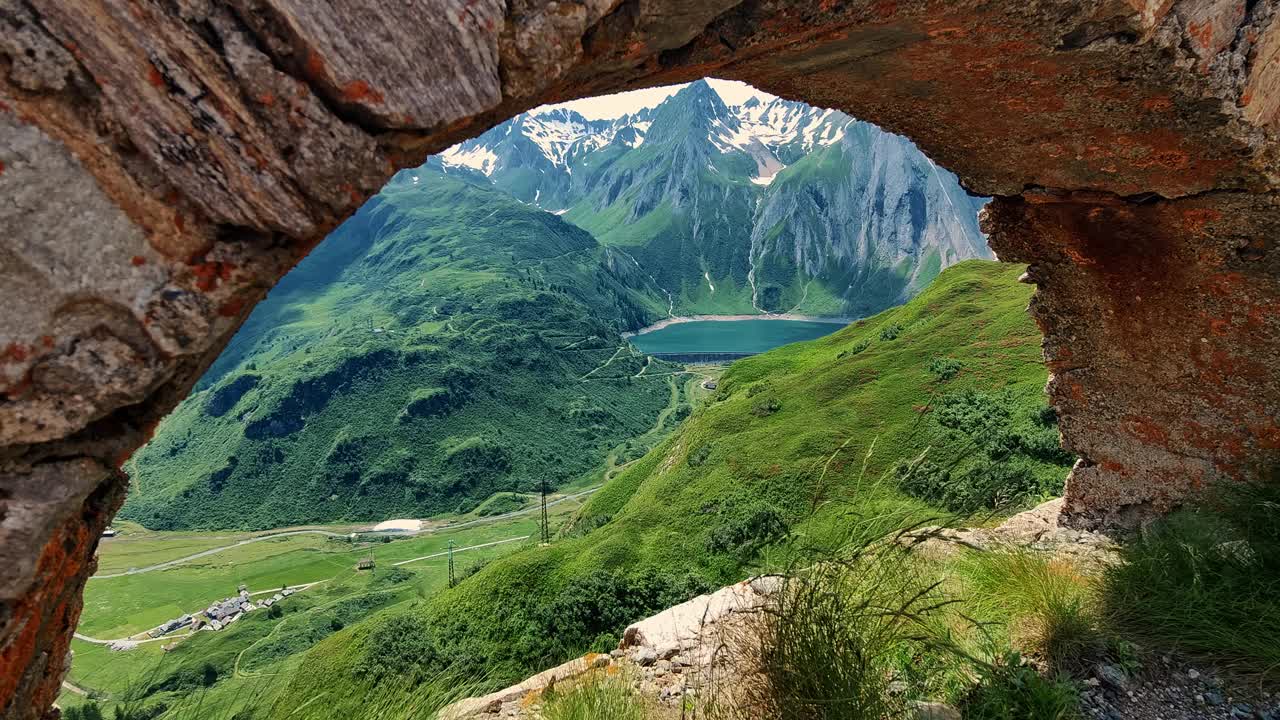 雄伟的山景通过自然石窗框架一个高山湖泊视频素材