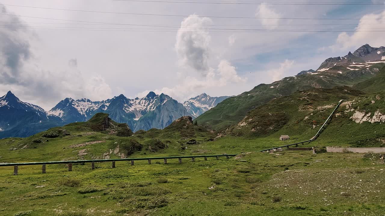 一条管道映衬着夏季郁郁葱葱的高山景观。视频素材