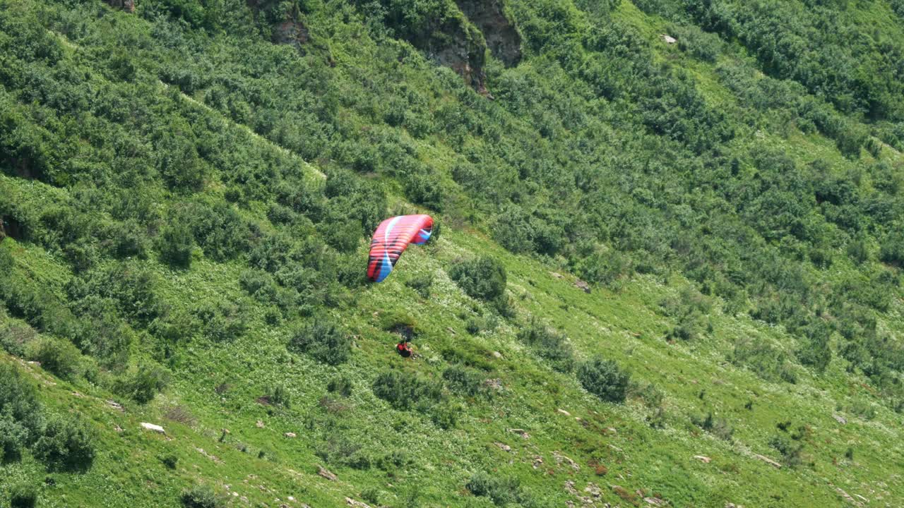 惊险的滑翔伞冒险在郁郁葱葱的绿色山景视频下载