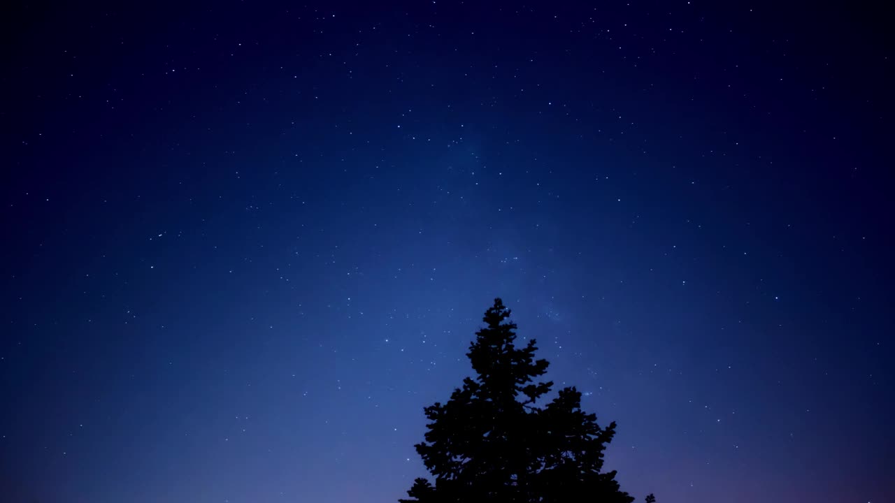 银河系的星星，流星雨的轨迹和乡村的剪影。视频下载