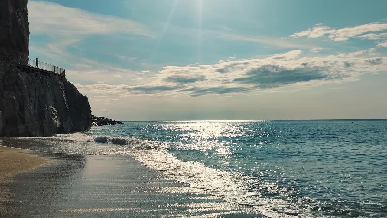 宁静的海景与岩石悬崖和沙滩阳光明媚的天空下视频素材