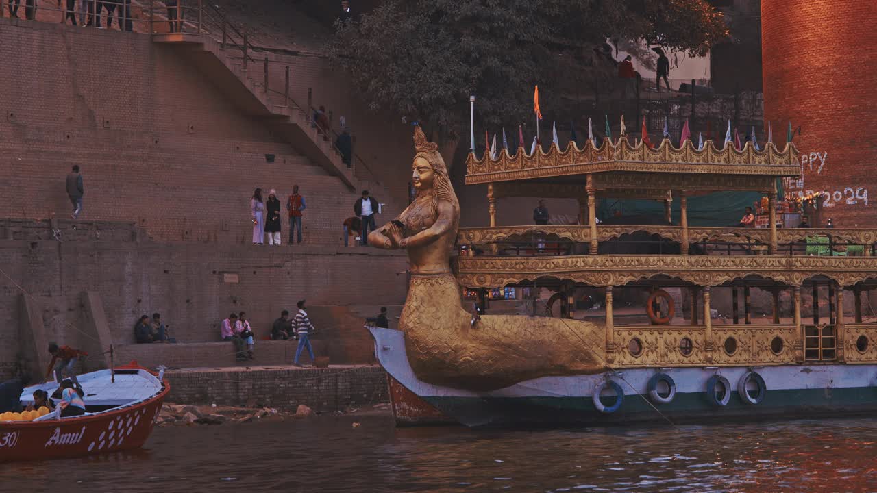 印度瓦拉纳西。船只停泊在恒河附近的Lassi Ghat和Tulsi Ghat。金色装饰的游船，前面有恒河女神雕像，供人们乘船游览。在印度的家庭度假。晚上在神圣的瓦拉纳西高止山脉视频下载